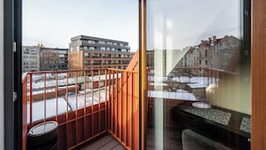 A balcony with a wooden railing, a small table, and a chair.