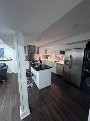 Een moderne keuken met witte kasten, een centraal eiland, roestvrijstalen apparatuur en een donker houten vloer.