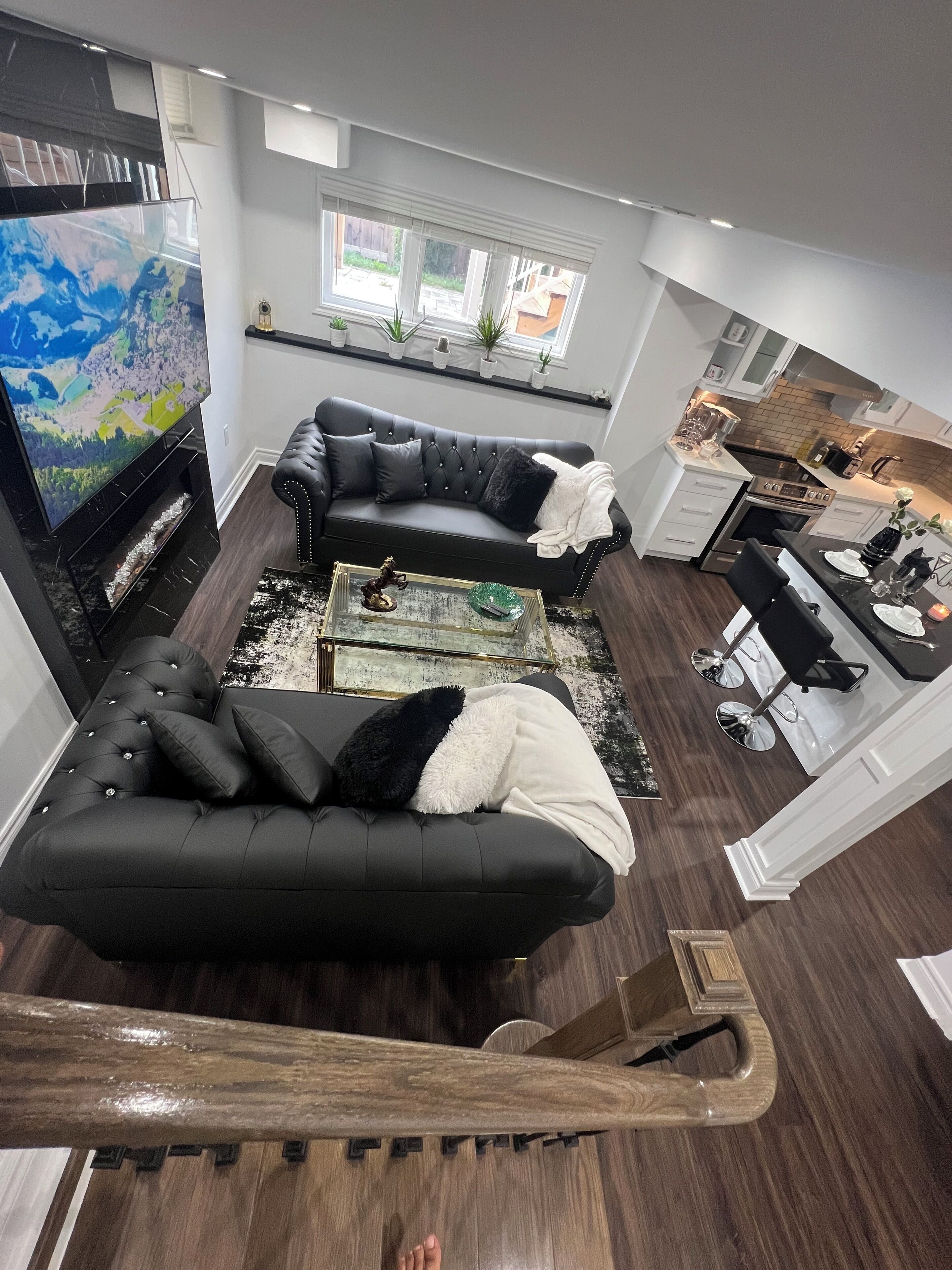 A modern living room with a black leather sofa, a coffee table, and a TV.