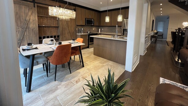 A modern kitchen with a central island, wooden cabinetry, and pendant lighting. - Warm & Stylish 4BR Home | 3BA • Near Toronto (Ajax)
