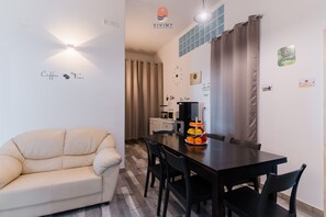 Una sala de estar moderna con un sofá, una mesa de comedor con sillas, una cafetera y un reloj en la pared.