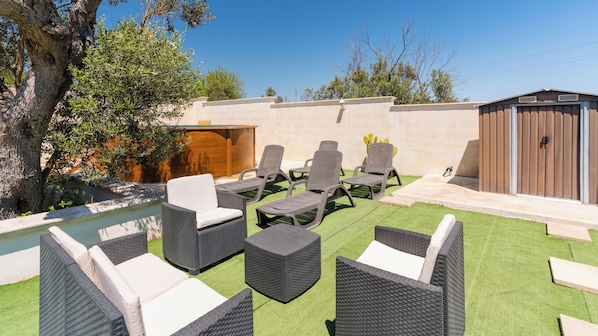 Un patio con mobili da esterno, una piscina e un capanno di legno.