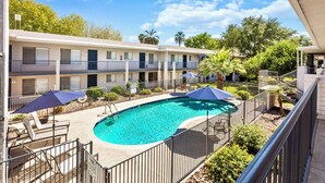 A swimming pool surrounded by lounge chairs and umbrellas, with a multi-story building in the background. - Downtown Mesa Apartment - Pool, W/D, 65” TV, Walk to Dining (Mesa)