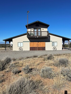 A two-story house with a balcony, a garage, and a large wooden door. - Chrome Bear Ranch Guest House (Montrose)