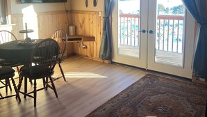 Ein Essbereich mit Holztisch und -stühlen, einem Deckenventilator und Blick durch eine Glastür auf einen Außenbalkon.