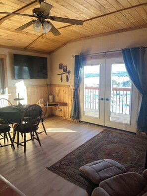 A dining area with a wooden table and chairs, a ceiling fan, and a view through a glass door to an outdoor balcony. - Chrome Bear Ranch Guest House (Montrose)