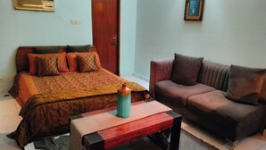 Une chambre à coucher comprenant un lit, un canapé, une table basse, une porte et un climatiseur fixé au mur.