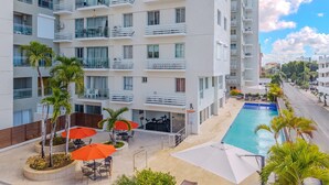 A multi-story hotel with balconies, a swimming pool, outdoor seating, and palm trees. - OCEAN AND BEACH VIEW ROOFTOP (Boca Chica)