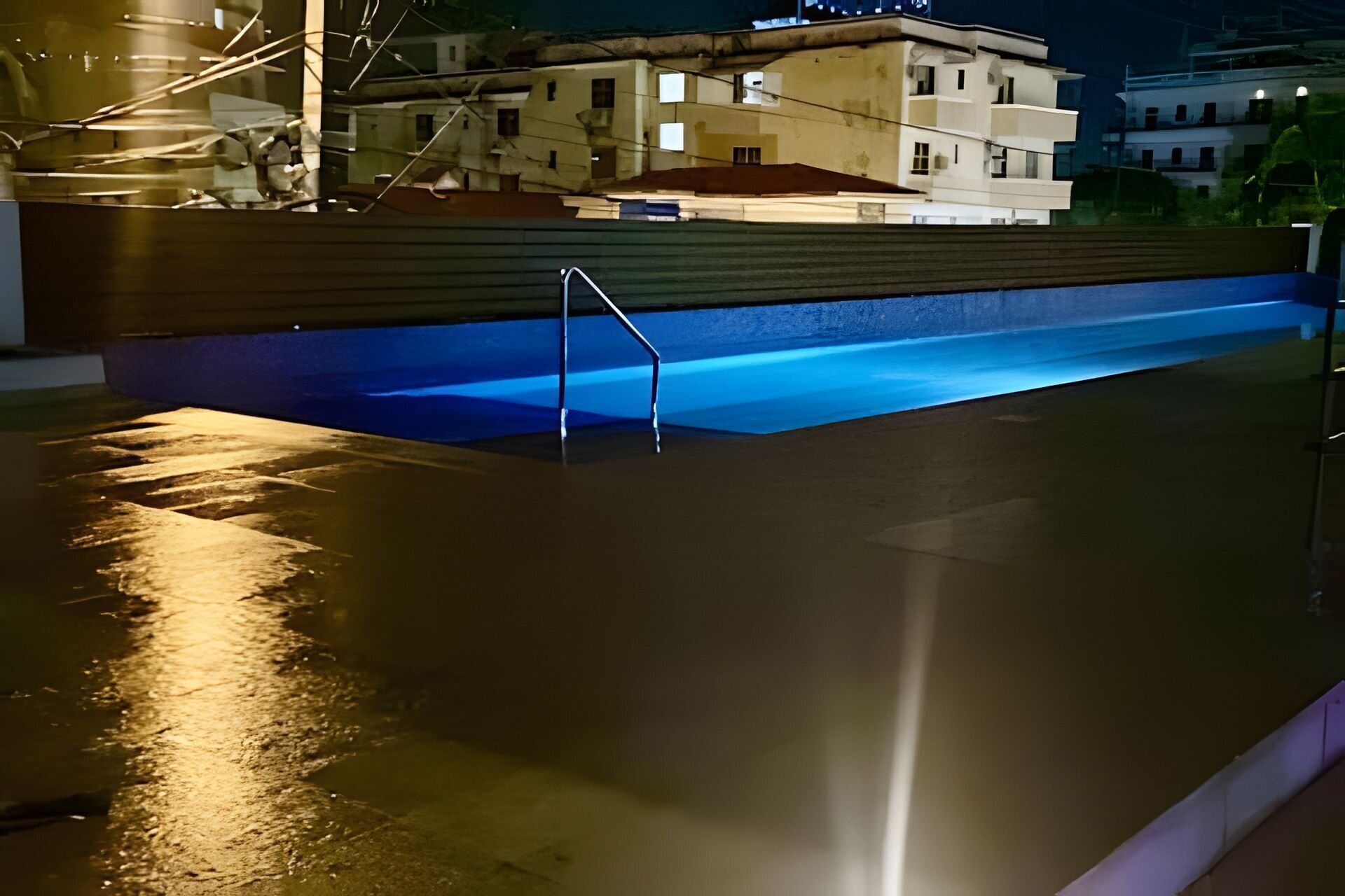 A swimming pool with a diving board and a building in the background.