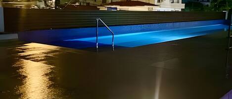 A swimming pool with a diving board and a building in the background.