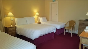 Een hotelkamer met twee eenpersoonsbedden, een stoel, een bureau en een kledingkast.