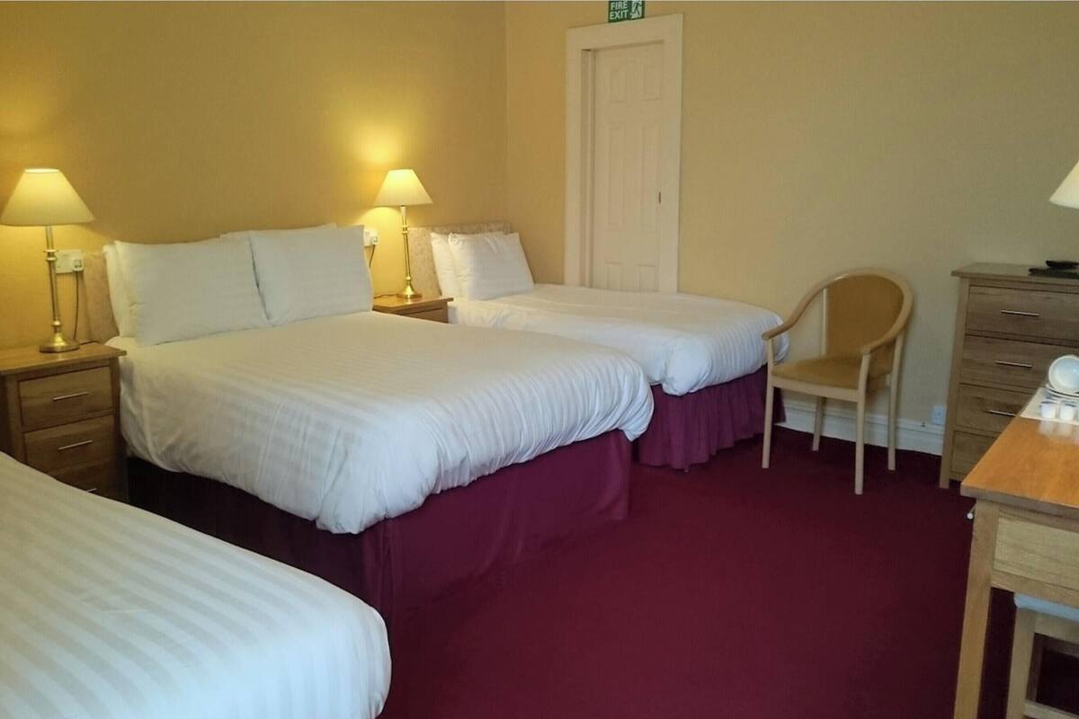 Une chambre d’hôtel avec deux lits simples, une chaise, un bureau et une armoire.