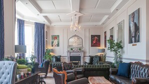 Een ruime woonkamer met een open haard, leren banken en een kroonluchter.