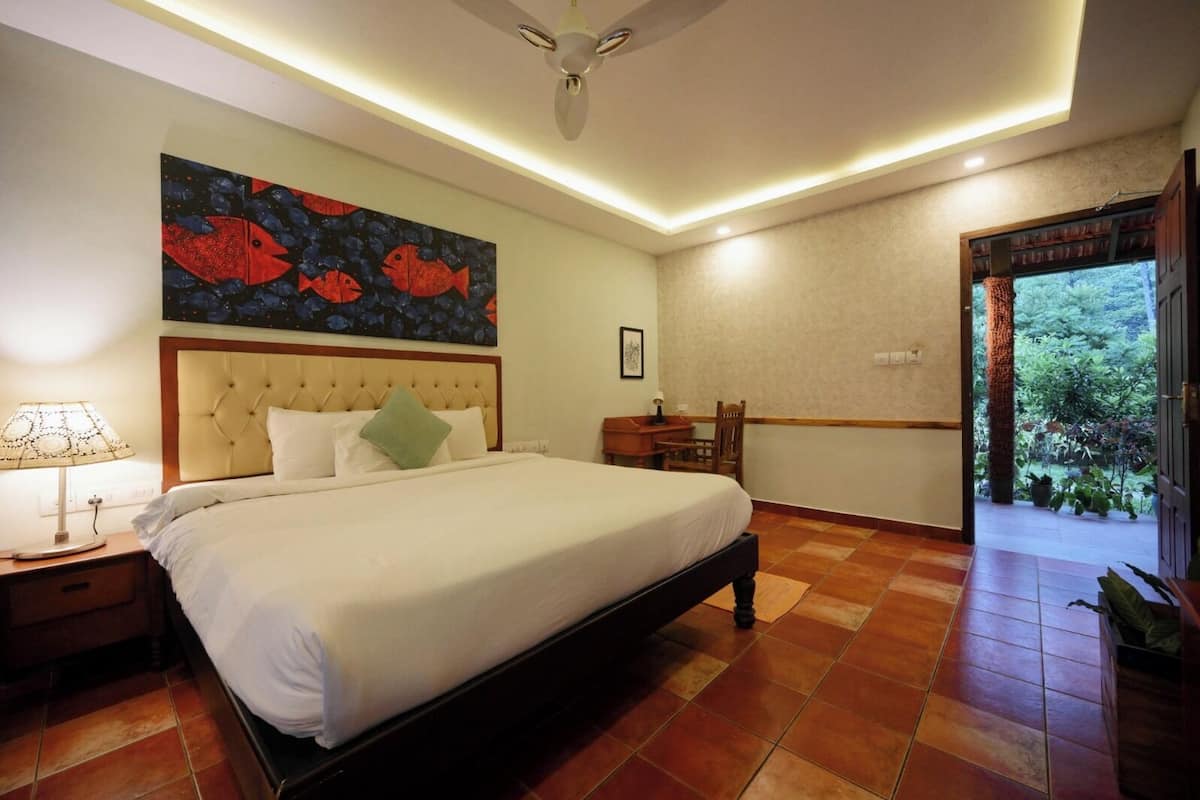 A bedroom with a bed, nightstands, a desk, and a painting of fish on the wall.