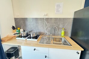 Uma cozinha com duas placas de indução, uma pia e um balcão com diversos objetos.