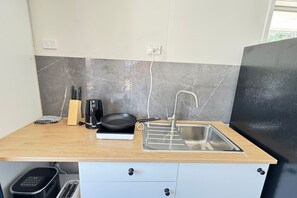 Ett kök med en diskho, en kaffebryggare och en brödrost på en bänkskiva av trä.