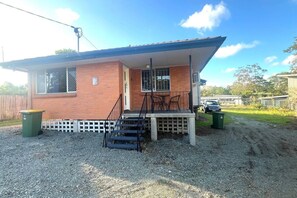 Uma casa térrea com varanda, um espaço de estar ao ar livre e uma entrada com calçamento de pedras.
