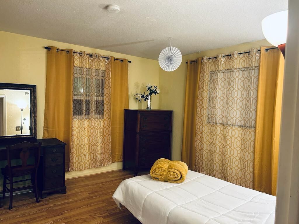 A room with a bed, a desk, a dresser, and a mirror.