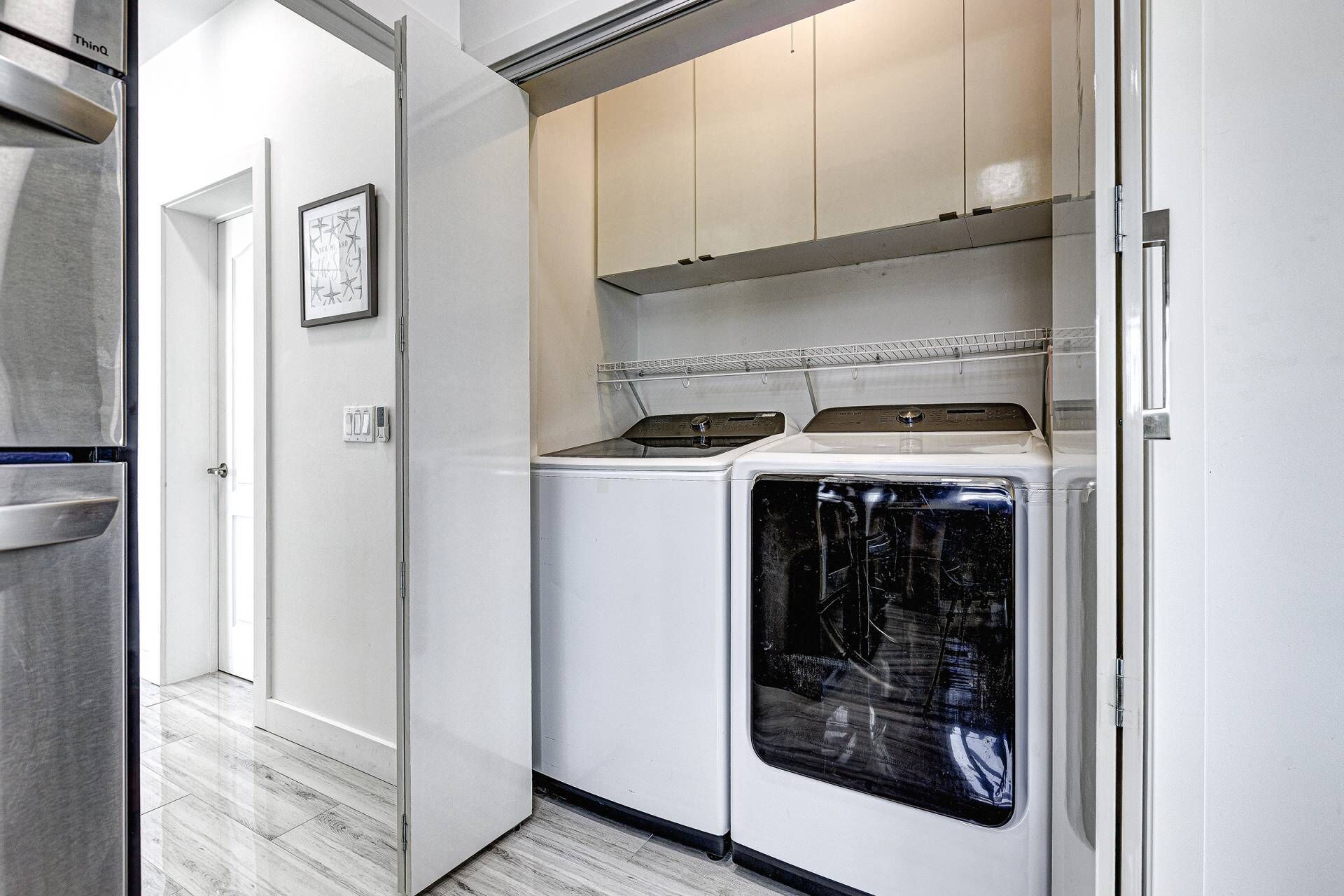A compact laundry room with a washer and dryer, a metal cabinet, and a door leading to another room.