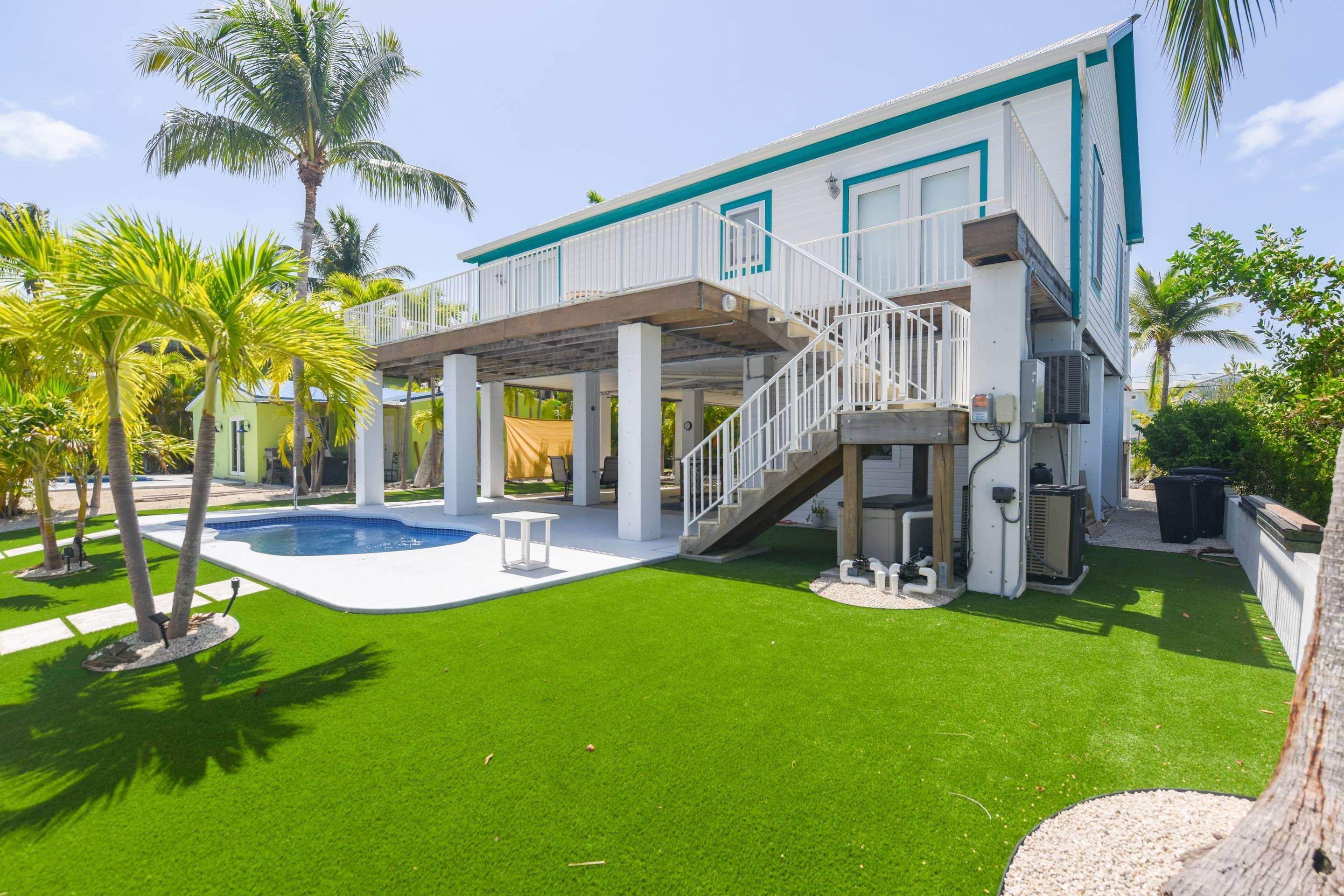 A two-story house with a covered patio, a swimming pool, and a well-maintained lawn.
