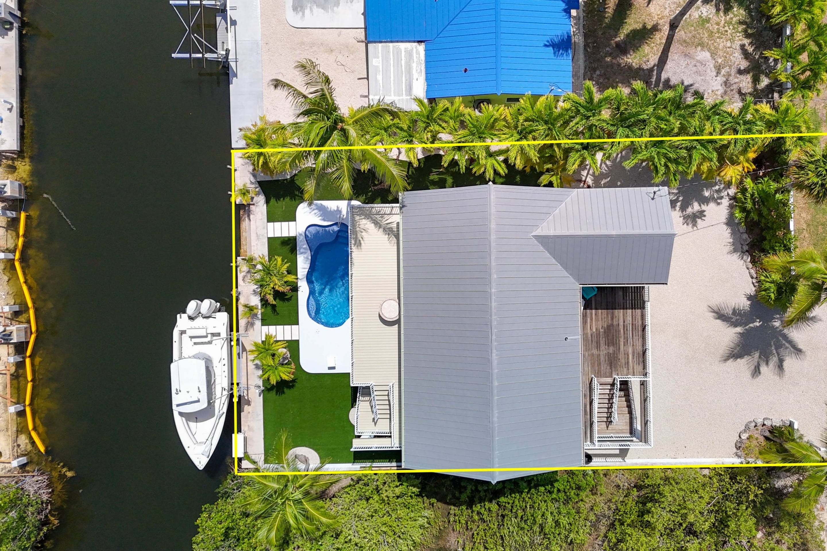 Ein Wohnhaus mit Schwimmbad, anglegtem Boot und überdachter Terrasse.