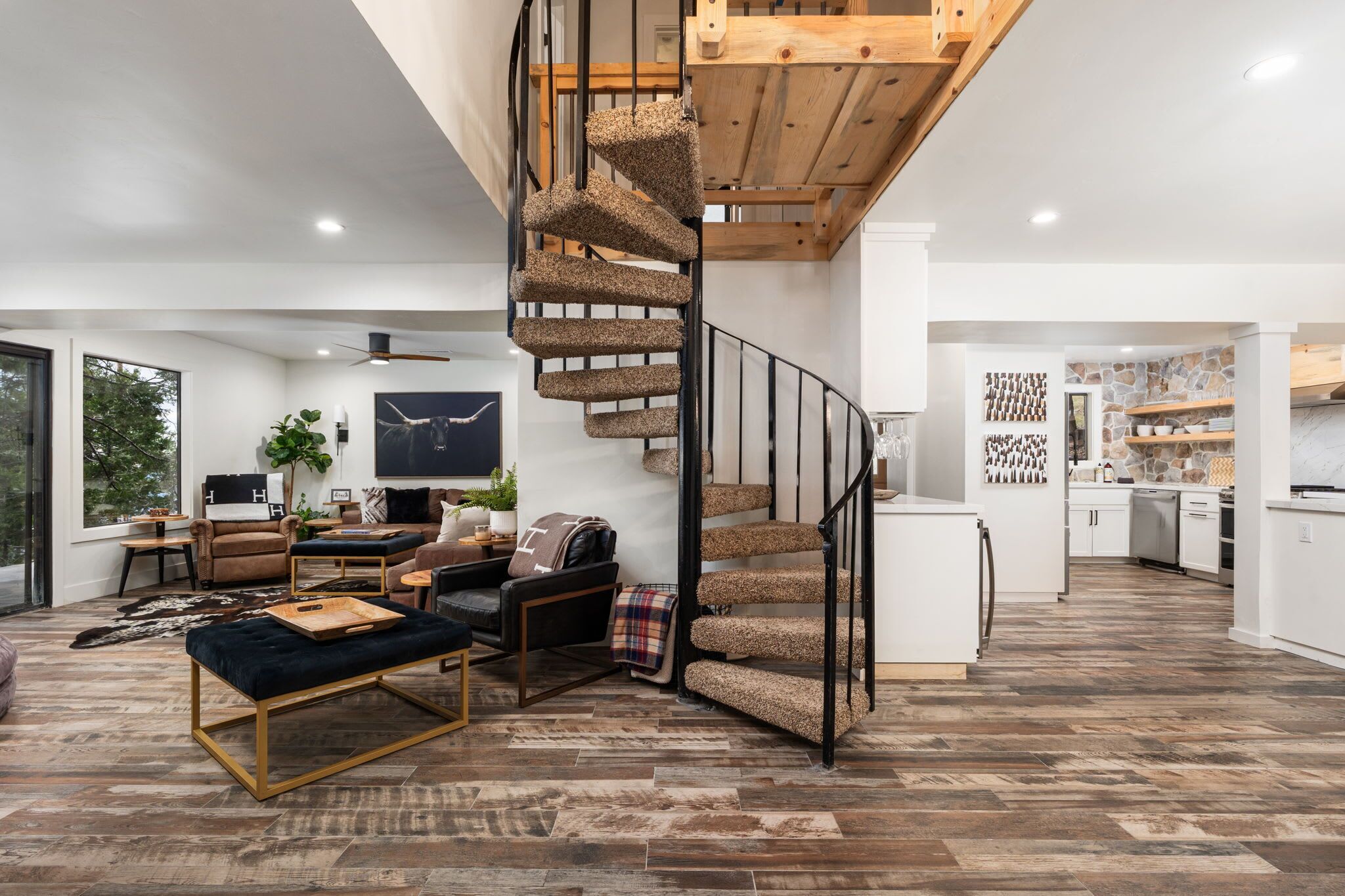 Un salon moderne avec un escalier en colimaçon, un grand téléviseur et un coin salon confortable.
