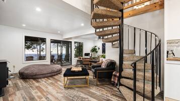 Un salon moderne doté d’un escalier en colimaçon, de grandes fenêtres et d’un coin salon confortable.