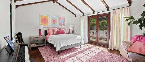 Un dormitorio con un piano, una cama, un ventanal y vistas al verdor exterior.