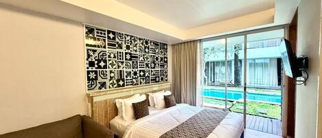 A bedroom with a large bed, a sofa, a patterned wall, and a view of a swimming pool.