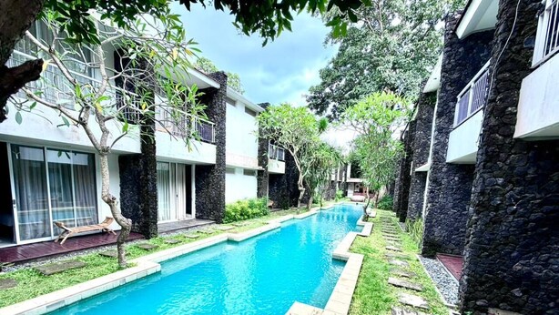 A swimming pool surrounded by stone buildings with balconies. - Dealton Hotel Sanur (Denpasar)