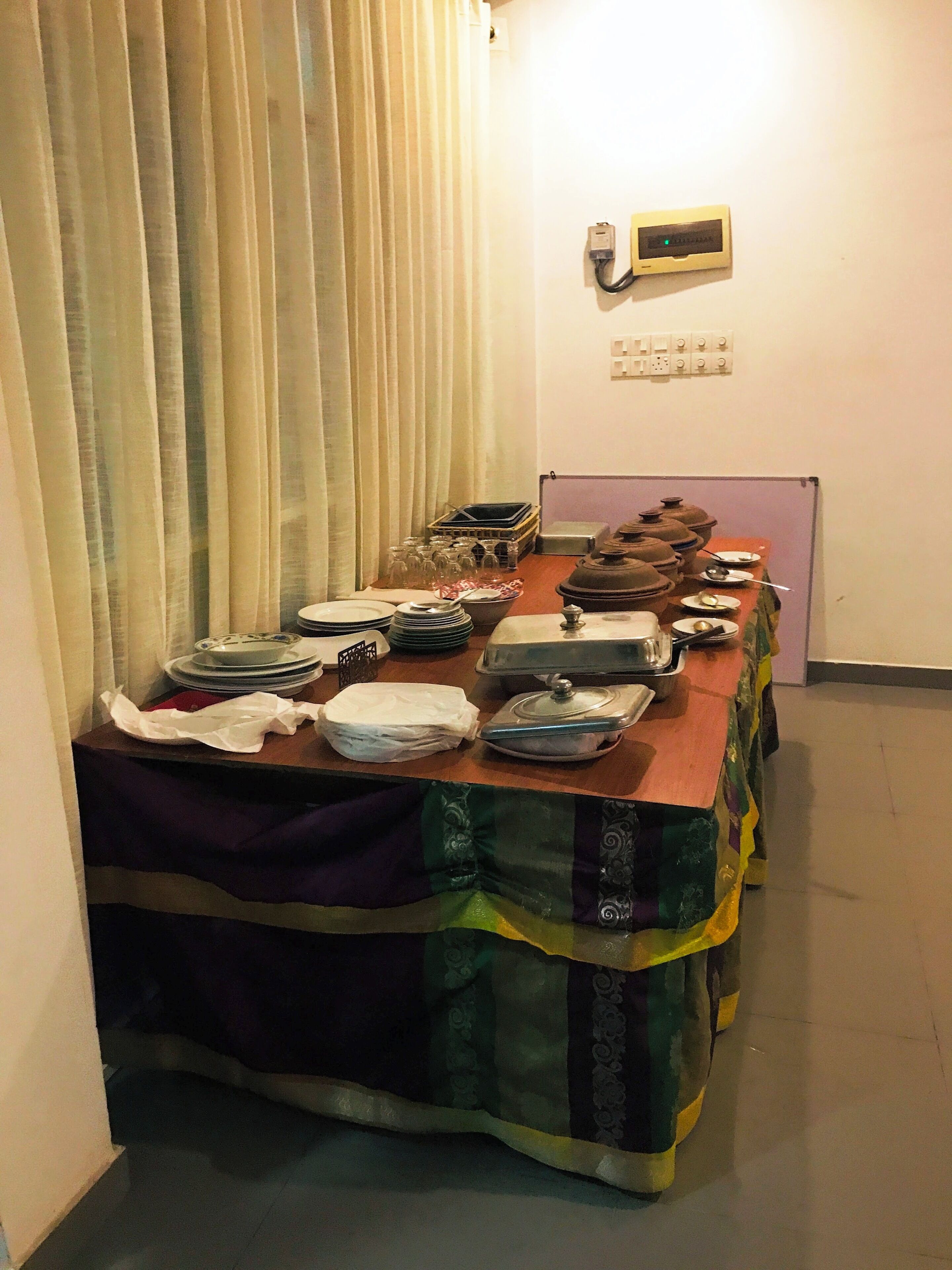 Una taula llarga preparada amb plats, gots i un recipient per als aliments, probablement per a una menjada.
