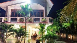 A two-story building with a balcony, surrounded by palm trees and a well-lit entrance. - Green star villa (Jaffna)