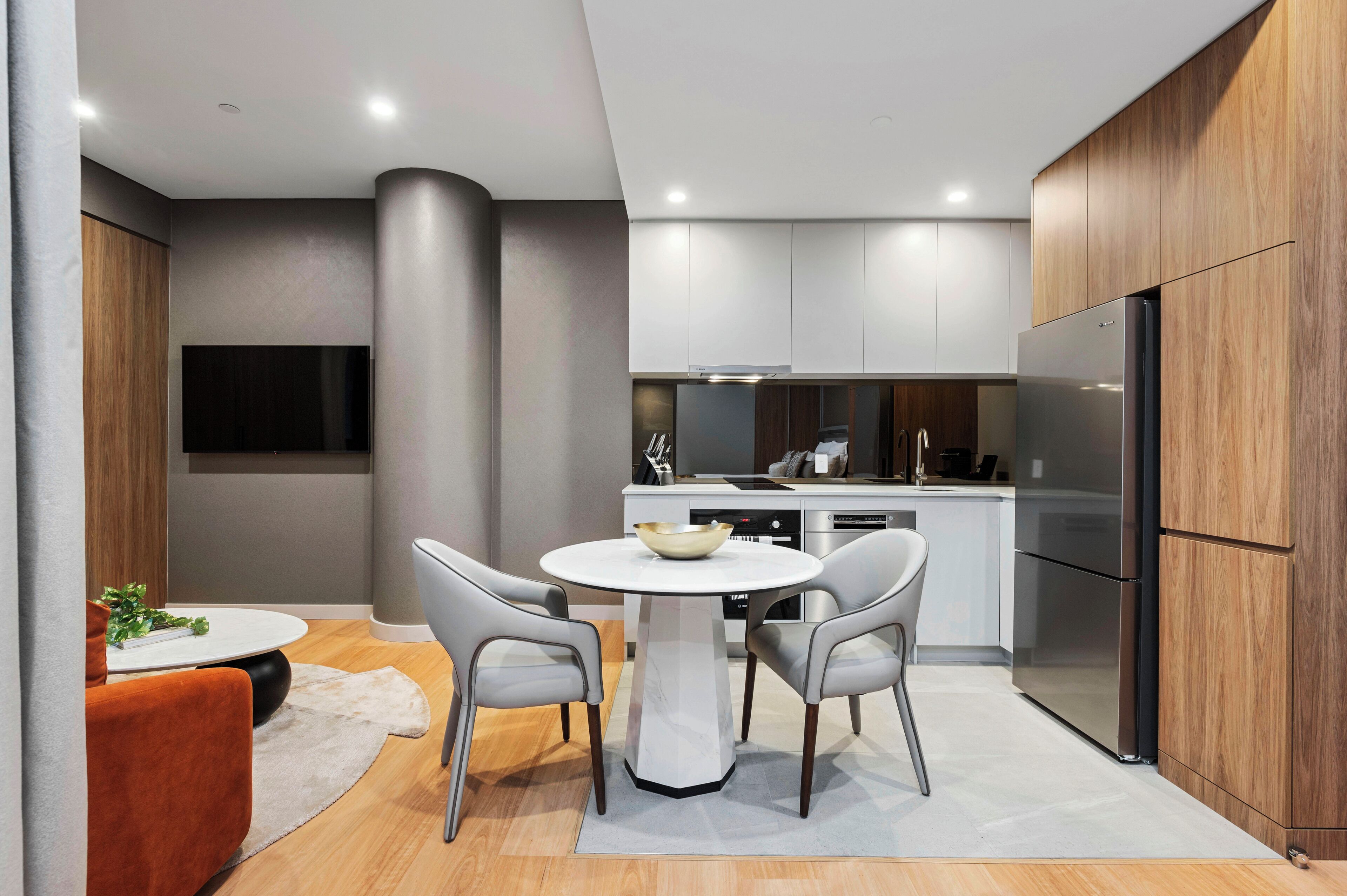 A modern kitchen with grey cabinets, a built-in oven, and a large refrigerator.