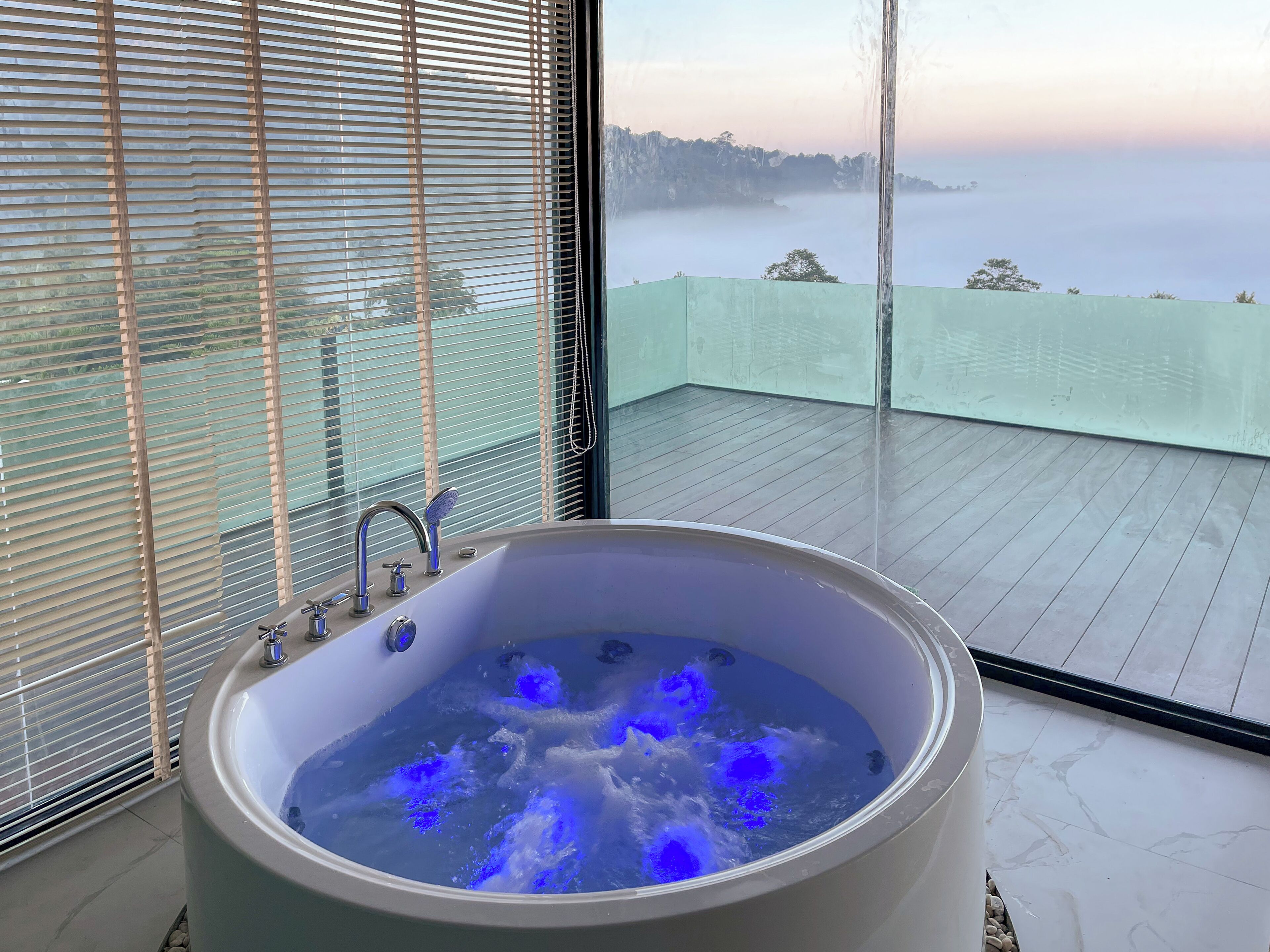 A large bathtub with a view of a misty landscape through a window.