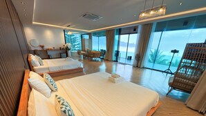 Una habitación de hotel moderna con una cama grande, una zona de estar con vistas y un balcón.