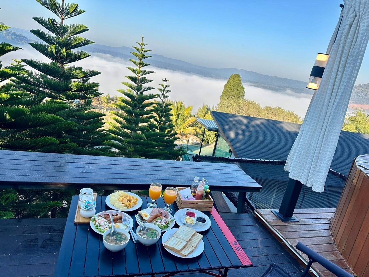 Una mesa de desayuno con diversos platos y una vista de montañas y nubes.