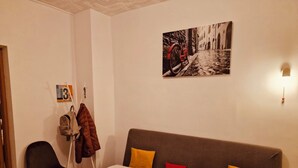 Ein gemütliches Zimmer mit einer Couch, einem Sessel und einem Kleiderhaken.