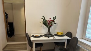 Ein Essbereich mit einem weißen Tisch, schwarzen Stühlen, einer Blumenvase, einer Schüssel mit Müsli, einer Bananenschale und einer Tasse.