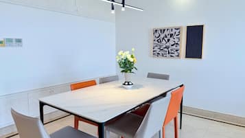 Een moderne vergaderruimte met een marmeren tafel, zes stoelen, een bloevas en abstracte kunst aan de wanden.