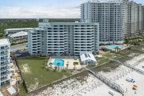 Ein Hochhaus-Hotel mit mehreren Balkonen, einem Schwimmbad und einer Strandanlage.
