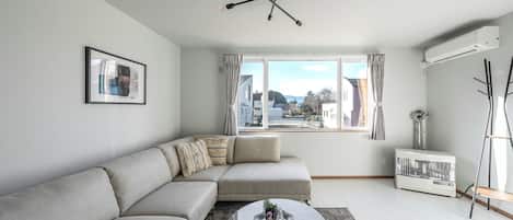 A modern living room with a sectional sofa, a round coffee table, and a large window with curtains.