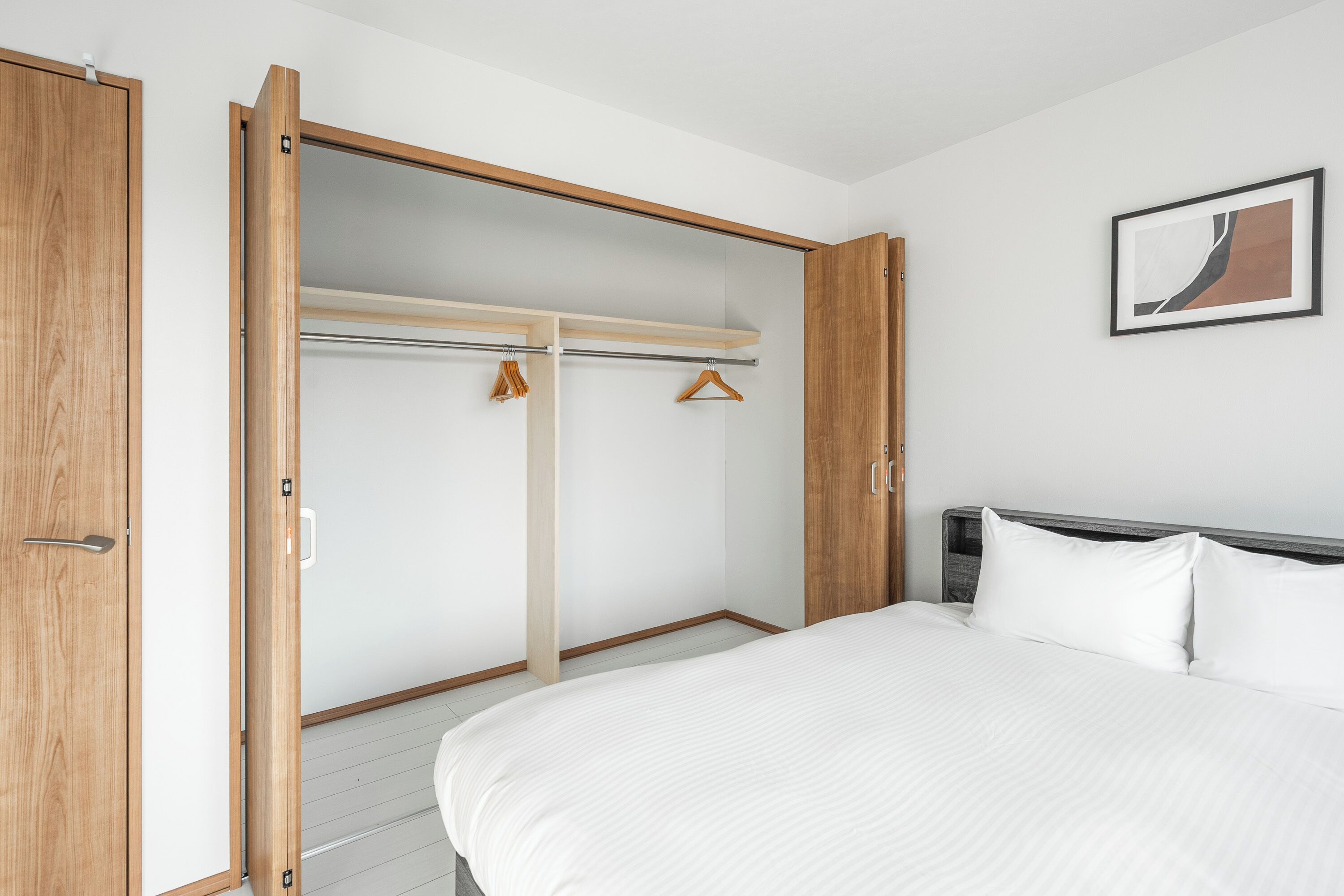 Ein Schlafzimmer mit einem Bett, einem Holzschrank und einem Kleiderständer.