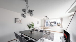 A modern living room with a dining area, a sofa, and a TV displaying 'NETFLIX'. - HILLS NISEKO C (Niseko)