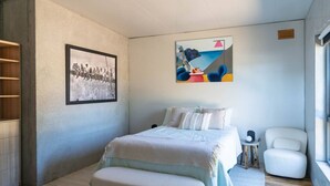 A bedroom with a bed, a chair, a small table, a picture on the wall, and a window. - Mabels Lookout - Sauna| Bath| Sunsets| Views| Fire (North Bruny)