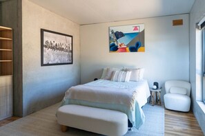 A bedroom with a bed, a chair, a small table, a picture on the wall, and a window. - Mabels Lookout - Sauna| Bath| Sunsets| Views| Fire (North Bruny)