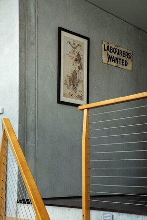 Una escalera con barandilla de madera y un letrero en la pared que dice 'LABOURERS WANTED'.