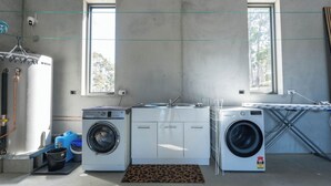 A laundry room with a washing machine, dryer, and a large water heater. - Mabels Lookout - Sauna| Bath| Sunsets| Views| Fire (North Bruny)
