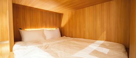 A single bed in a room with wooden paneling on the walls and ceiling.