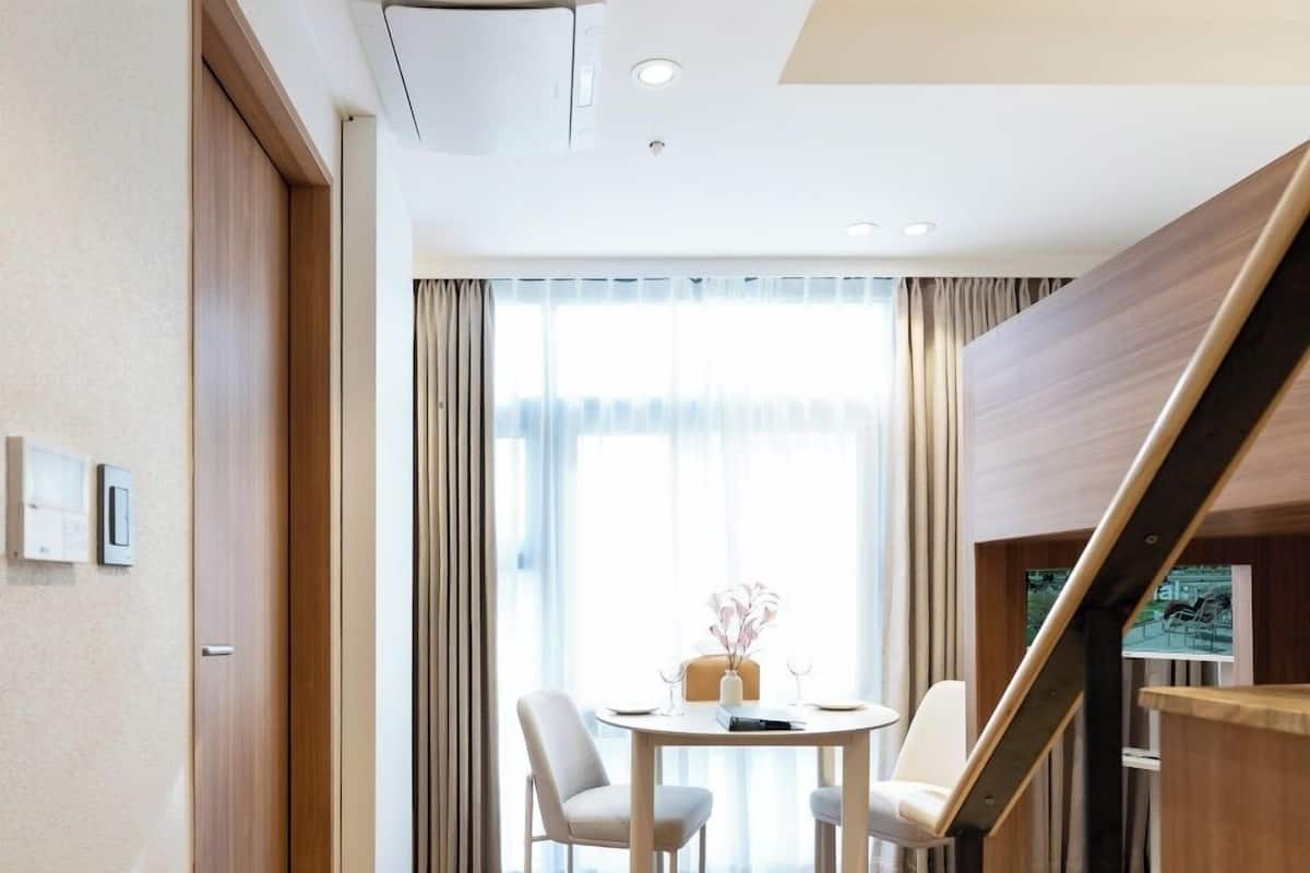 Ein modernes Hotelzimmer mit Holzboden, einer Essecke mit Tisch und Stühlen sowie einer Holztreppe mit Geländer.
