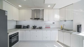 Una cocina moderna con armarios blancos, horno empotrado, microondas y cocina a gas.